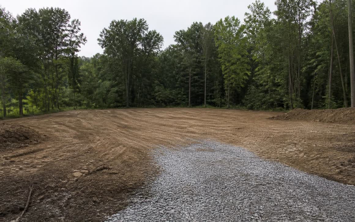 Graded building pad and gravel driveway line after site work by Landmark Enterprises
